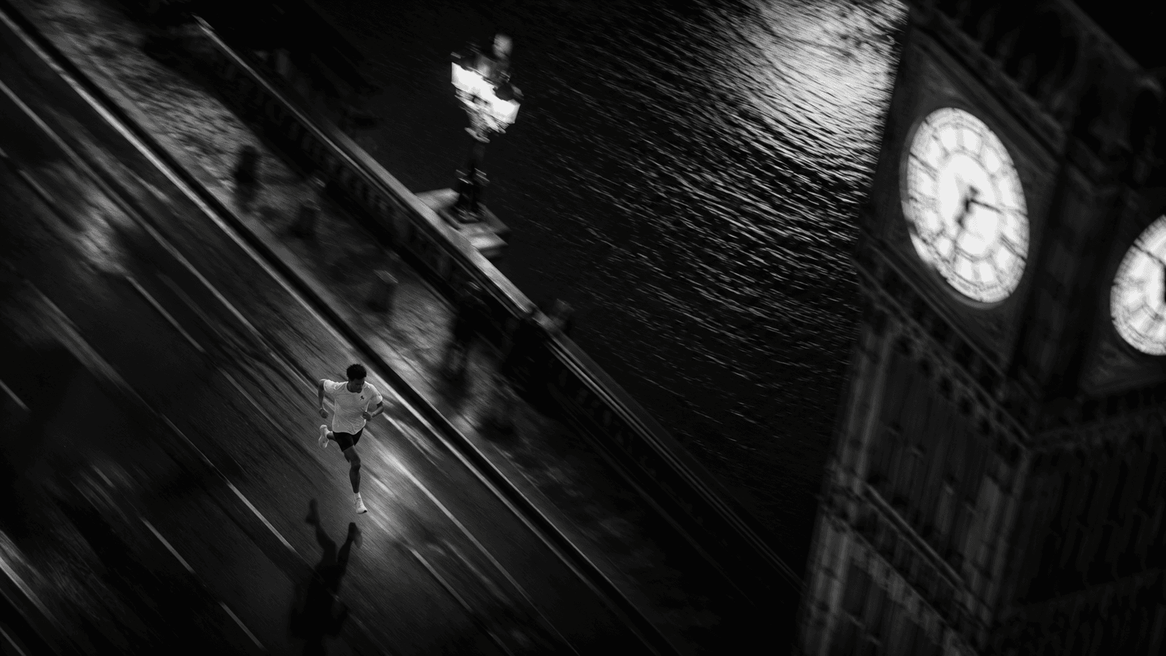 A lone runner crossing a London bridge at night beneath Big Ben