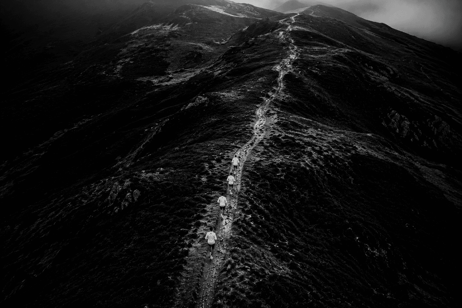 Aerial view of a single-track trail climbing high into remote mountains